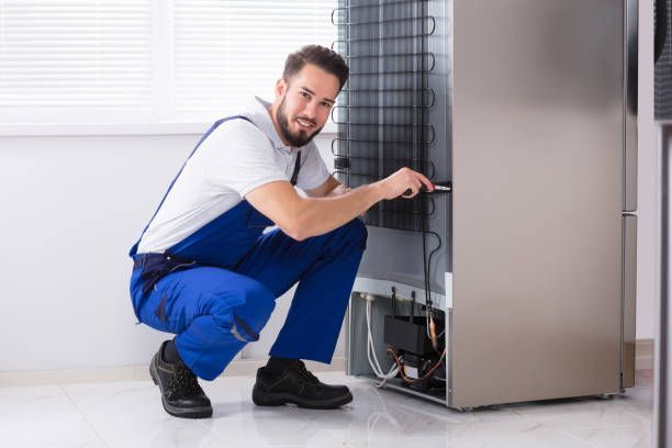 photo of male technician fixing refrigerator in kitchen